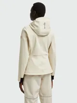 Chaqueta técnica Moncler modelo Zumeles, de color beige, con capucha ajustable, cierre frontal con cremallera termosellada y puños con detalle en contraste. Presenta un diseño entallado con bolsillos laterales y logo estampado en la manga.