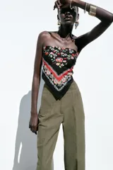 Pantalón de lino negro, de tiro alto, con bolsillos delanteros de vivo, pernera recta y cierre frontal con cremallera, botón interior y gancho metálico.