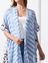 Kimono tejido con estampado de rayas azules y blancas, mangas amplias estilo japonés y terminación de ruedo con borlas azules.