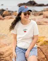 Remera de jersey de algodón color crudo, con cuello redondo y mangas cortas. Presenta bordado de cerezas y texto en el frente.