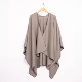 Ruana de corte asimétrico en color gris, con terminaciones de costura reforzada en los bordes y diseño abierto.