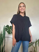 Chaleco tejido color verde oliva, con cuello en v y diseño de trenzas y ochos. Silueta oversize.