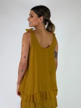 Top de viscosa color marrón tostado, sin mangas, con escote redondo y detalle de lazos para anudar en los hombros. Presenta un diseño de capas con volados en el ruedo.