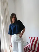 Top corto azul marino de punto, con mangas cortas amplias, cuello redondo y detalle de escudo bordado en la parte delantera.