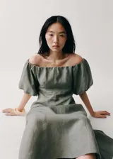 Vestido midi de lino color verde oliva, con escote palabra de honor y mangas cortas abullonadas. Presenta un diseño evasé con costuras verticales y cierre de cremallera en la parte posterior.