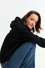 Canguro liso de color negro con capucha y bolsillo frontal tipo canguro, confeccionado en tejido de algodón.