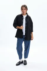 Sobrecamisa de jean color negro, con corte oversize, cuello camisero, cierre frontal con botones metálicos y bolsillos frontales con solapa.