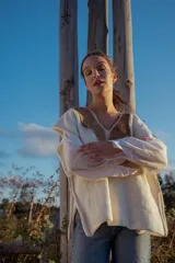 Chaleco tejido color crudo con aplique de cuero marrón en el cuello y detalle de pespunte en el contorno.