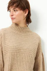 Polera gris de tejido tramado, cuello alto y mangas holgadas.