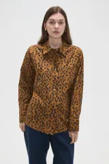 Camisa de algodón con estampado de manchas oscuras sobre fondo tostado, de corte holgado, manga larga, cuello clásico y cierre frontal con botones.