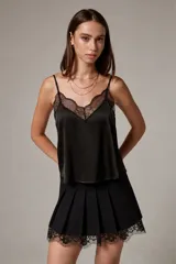 Top negro de tirantes finos con reguladores, confeccionado en poliéster con detalles de encaje y apliques de strass. Presenta escote en V y diseño entallado.