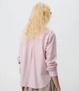 Camisa oversized de popelina de algodón, con diseño a rayas en tonos rosados y azules, cuello clásico, mangas largas con puños abotonados y cierre frontal de botones.