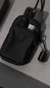 Mini bag o portacelular de formato vertical, confeccionada en cordura waterproof de alta resistencia. Cuenta con dos compartimentos con cierres reforzados y cordón de alta densidad ajustable mediante mosquetones metálicos para usar cruzado.