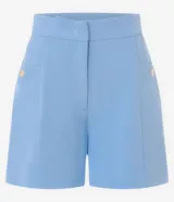 Short de sastrería color marrón, de cintura alta con cierre tradicional. Presenta recortes delanteros con costura aparente, bolsillos laterales con tachuelas metalizadas y bolsillos traseros decorativos.