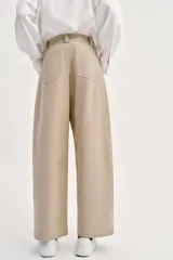 Pantalón barrel color azul marino, de tiro bajo, pernera holgada con diseño redondeado que se estrecha hacia el tobillo, con bolsillos delanteros y cierre frontal.