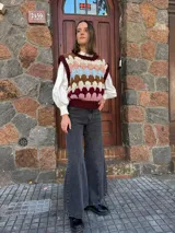 Chaleco tejido de punto con diseño multicolor en bloques, cuello redondo y terminaciones acanaladas. Presenta un patrón geométrico en tonos bordó, rosa, celeste, marrón y crema.