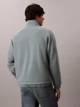 Buzo polar de Calvin Klein con cuello alto y cierre de media cremallera frontal. Presenta un diseño de manga larga con puños elásticos y un parche con el logo de la marca en el pecho.