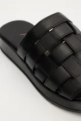 Sandalias planas de cuero con tiras plateadas tejidas en el empeine y base marrón.