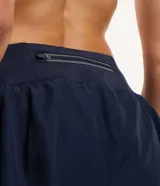 Bermuda deportiva tipo runner de microfibra color azul marino, con cintura elástica, bolsillo con cierre y diseño holgado con bajo redondeado.