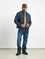 Campera capitoneada de color azul oscuro, con cierre frontal de metal y botones a presión. Presenta bolsillos laterales y en el pecho con cierres metálicos.