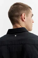 Camisa de manga larga color gris oscuro, confeccionada en tejido liviano con textura sutil, cuello tradicional y cierre frontal de botones.