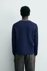 Camiseta de manga larga con cuello redondo y cierre frontal de botonadura tipo henley, confeccionada en tejido de punto con textura waffle.