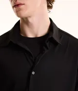 Camisa masculina de manga larga, cuello inglés y cierre frontal de botones, confeccionada en poliamida con elastano y tecnología performance.