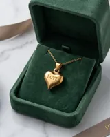 Collar de cadena fina con dije de corazón en relieve grabado con la palabra LOVE, acabado en tono dorado.