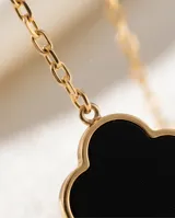 Collar de acero con baño de oro, con cadena eslabonada y tres dijes en forma de trébol u onix negro con borde dorado.