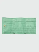 Billetera compacta Longchamp de cuero con textura de cocodrilo en color verde menta, con cierre de broche a presión y múltiples ranuras para tarjetas.
