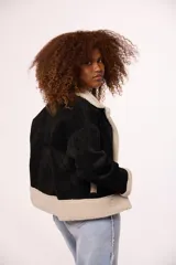 Campera tipo gamulán de gamuza color marrón con interior y solapas de corderito sintético color beige. Presenta cierre frontal con botones, mangas largas y corte holgado.
