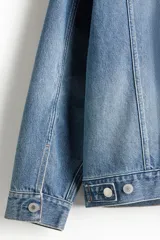 Campera de denim celeste con cuello clásico, cierre frontal con botones metálicos, bolsillos con solapa en el pecho y bolsillos laterales. Corte holgado.