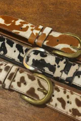 Cinto de cuero vacuno con pelo natural, con hebilla metálica y costuras reforzadas.