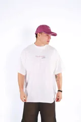 Remera de algodón blanca, corte oversize, con cuello redondo y manga corta. Presenta un pequeño estampado centrado en el pecho con texto en cursiva.