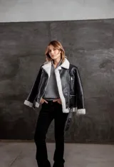 Campera tipo gamulán de cuero sintético negro con interior y solapas de corderito sintético en color blanco. Presenta cierre frontal, bolsillos laterales con cierre y cinturón ajustable en la cintura.