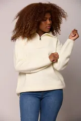 Buzo tejido de punto en color beige, con cuello alto y cierre frontal parcial, de manga larga y calce holgado.