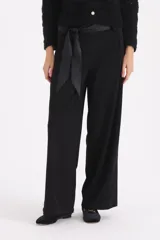 Pantalon de vestir negro de corte recto y tiro alto, con cintura ancha y cinto de lazo integrado en la misma tela.