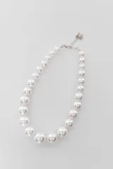 Collar de perlas blancas de tamaño graduado con cierre de mosquetón y cadena de alargue metálica plateada.