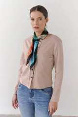 Cardigan de algodón color beige, de corte ajustado y manga larga, con cierre frontal de botones pequeños y cuello redondo.