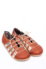 Zapato deportivo casual de cuero, con diseño de tiras laterales en contraste color marrón sobre base color crema. Presenta cierre con cordones y suela de goma con relieve.