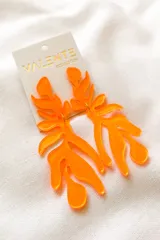 Aros colgantes de acrílico naranja con forma de hojas abstractas.