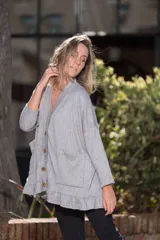 Saco de lanilla gris con textura de espiga, corte oversize, cuello en V, cierre con botones de madera, bolsillos frontales y volados en el ruedo.