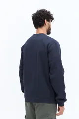 Buzo de algodón azul marino, corte regular, con cuello redondo. Presenta un bordado de flores y texto en el pecho.