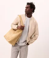 Campera tipo bomber masculina de color beige, con cuello, puños y ruedo acanalados. Presenta cierre frontal por cremallera, bolsillos laterales y acabado con tecnología repelente al agua.