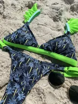 Bikini inferior con estampado de palmeras en tonos azules y negros, con tiras laterales ajustables.