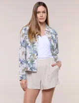 Camperita de lino liviana, marca Dash, con estampado botánico de hojas en tonos azules, verdes y tostados sobre base blanca. Presenta cierre frontal con botones, cuello clásico y bolsillos aplicados en el pecho.