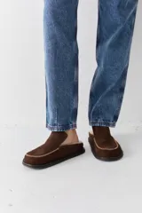 Zueco de cuero color marrón oscuro, con costuras decorativas en hilo rojo en el empeine y suela plana de goma.