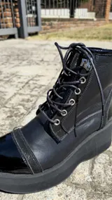 Borcegos de cuero tostado con plataforma bicolor, puntera y talón negros, detalles en animal print y cordones oscuros.