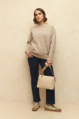 Polera beige de tejido de punto con cuello alto y mangas largas.