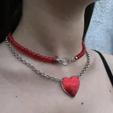 Set de dos collares: uno corto de cuentas verdes con dije de cristal facetado y otro más largo de cadena plateada con dije de corazón verde holográfico.